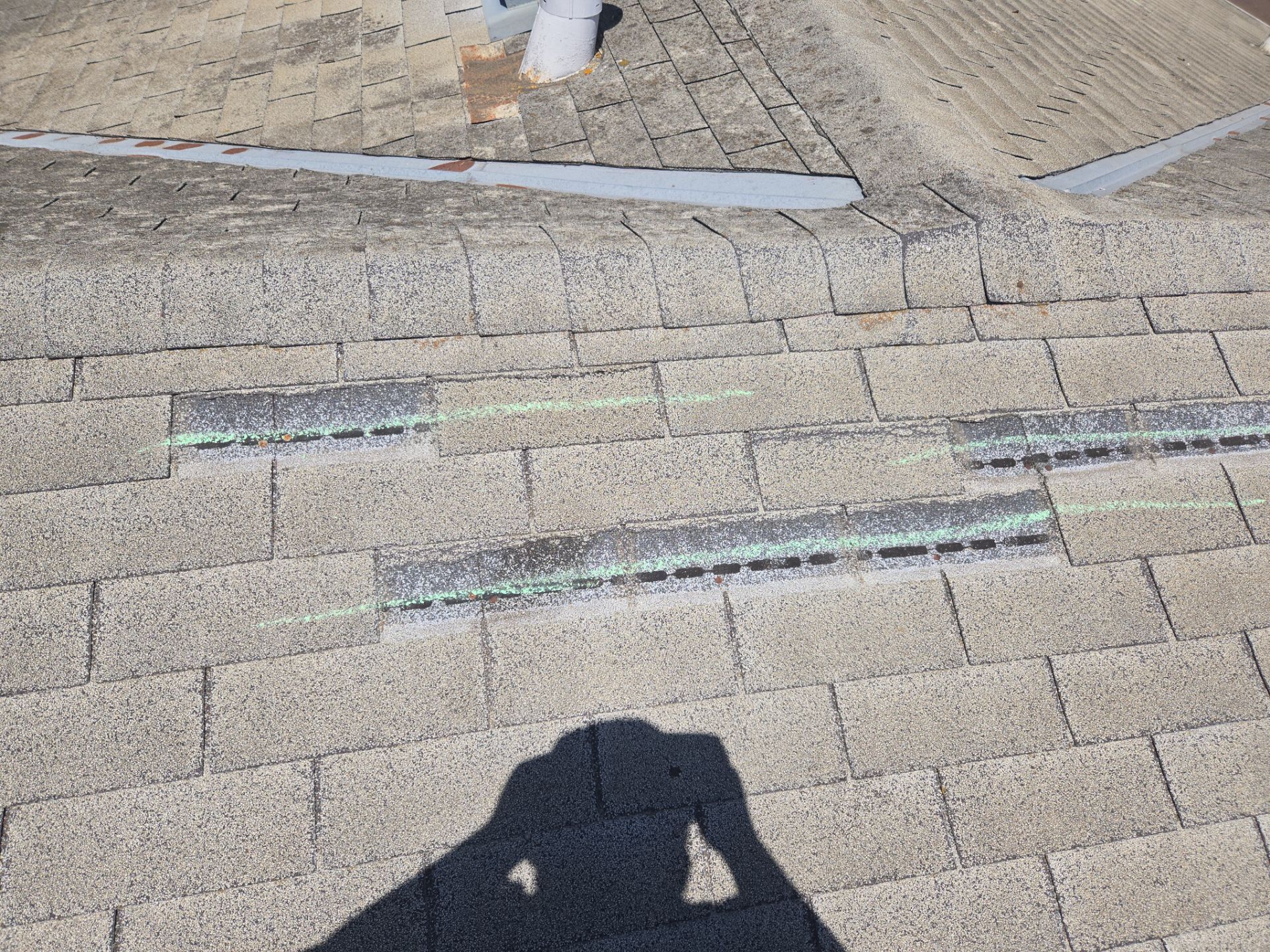Wide view of roof valley and hip sections marked for storm damage during a claim inspection