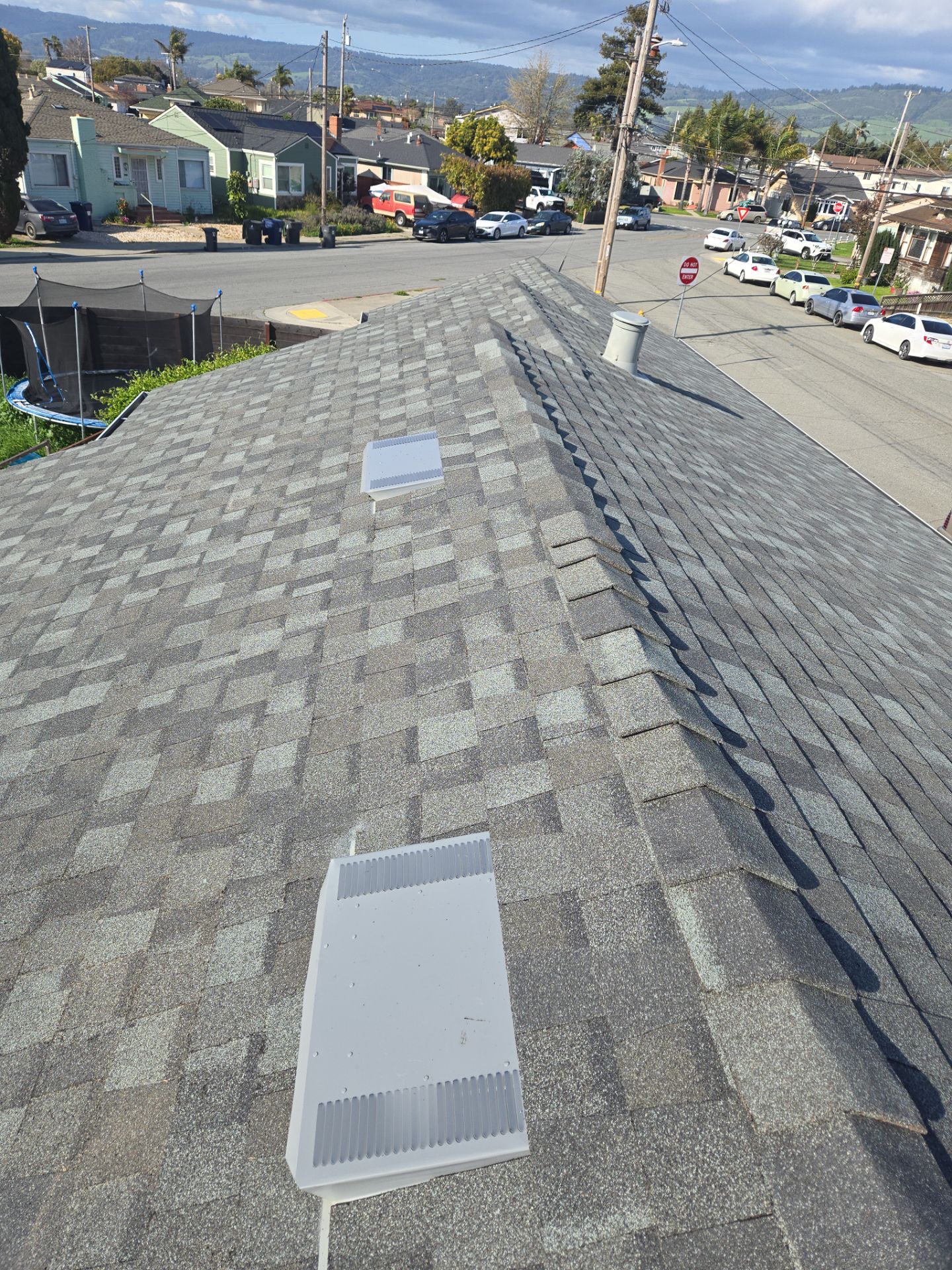Wide view of roof vents and ridge line inspected for wind damage overlooking the neighborhood
