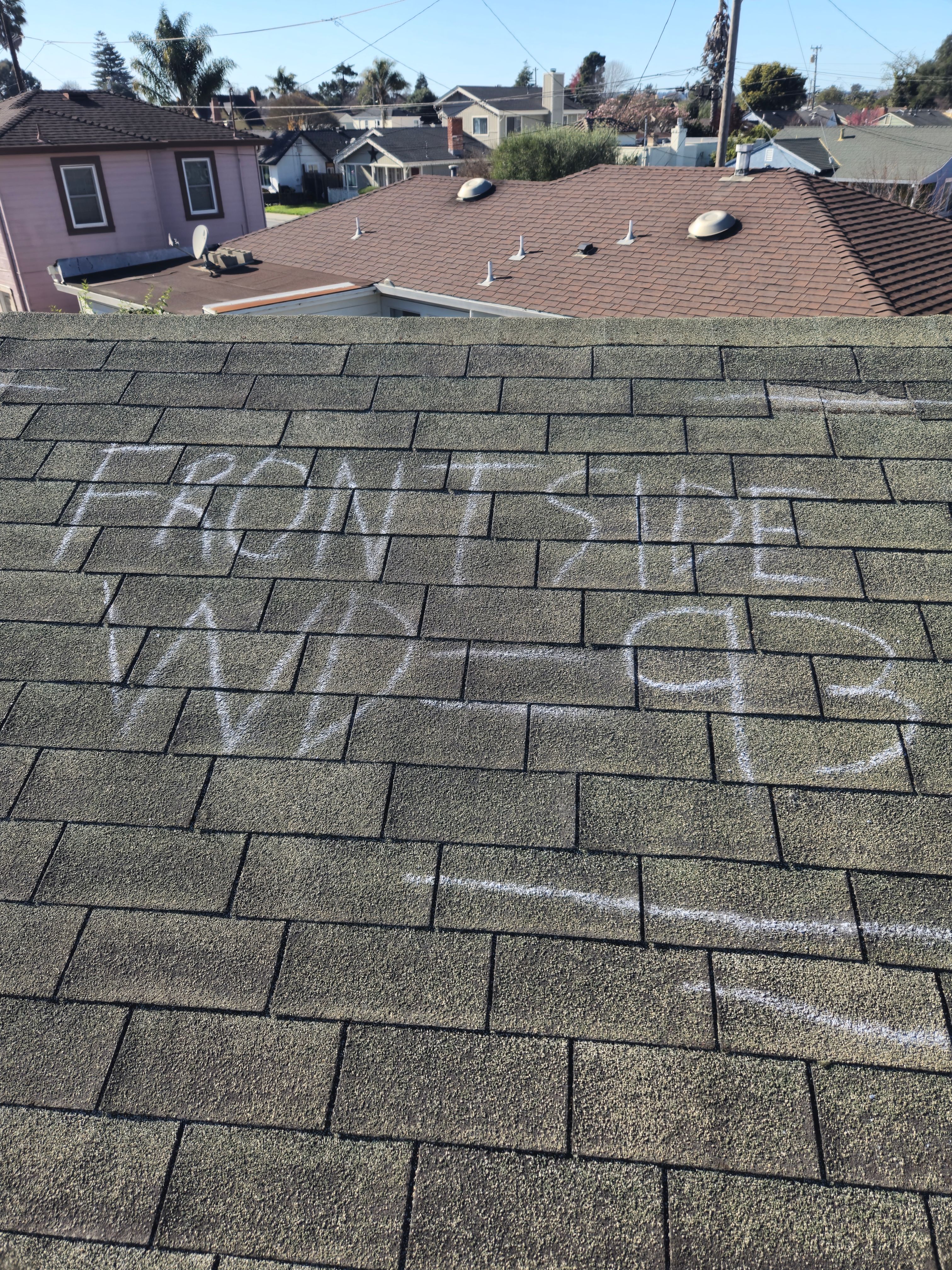 Chalk-marked wind damage labeled Front Side WD-93 documented during a roof inspection