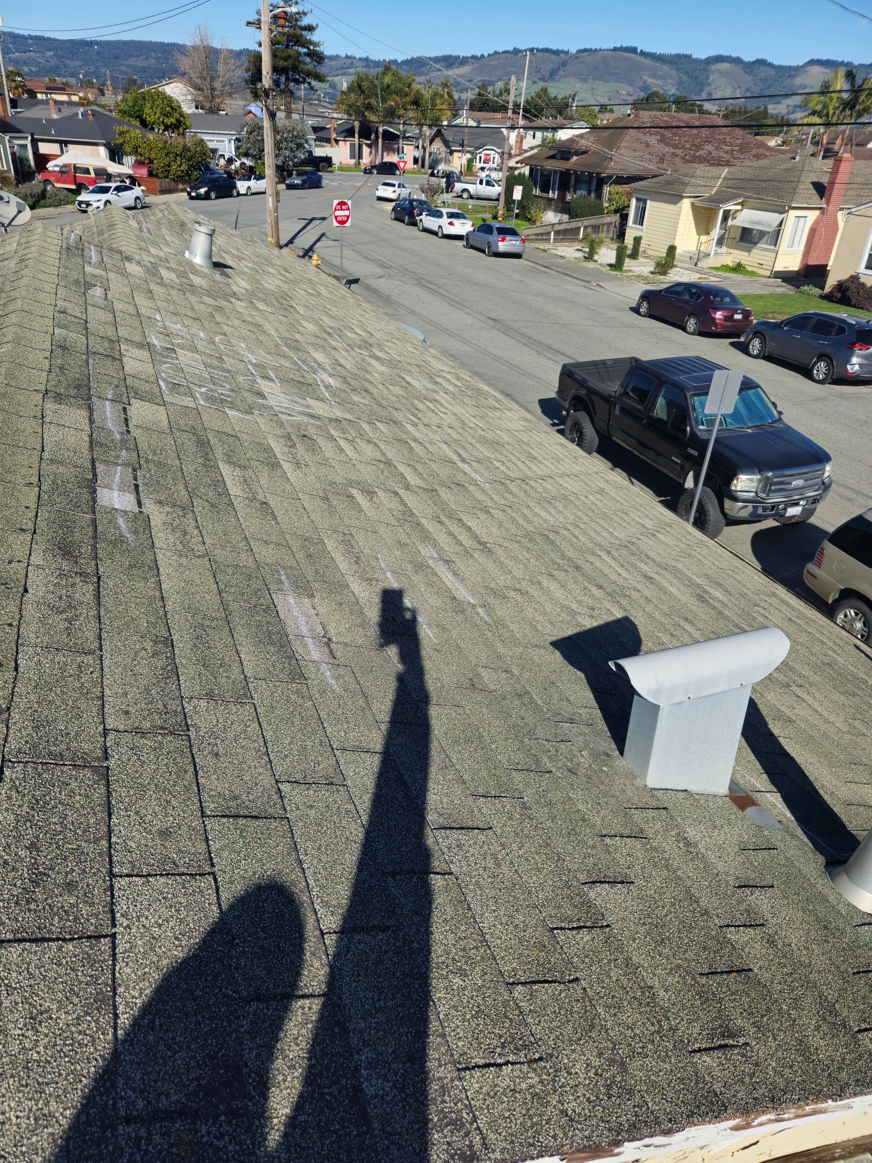 Multiple storm damage marks documented across roof shingle courses overlooking the street