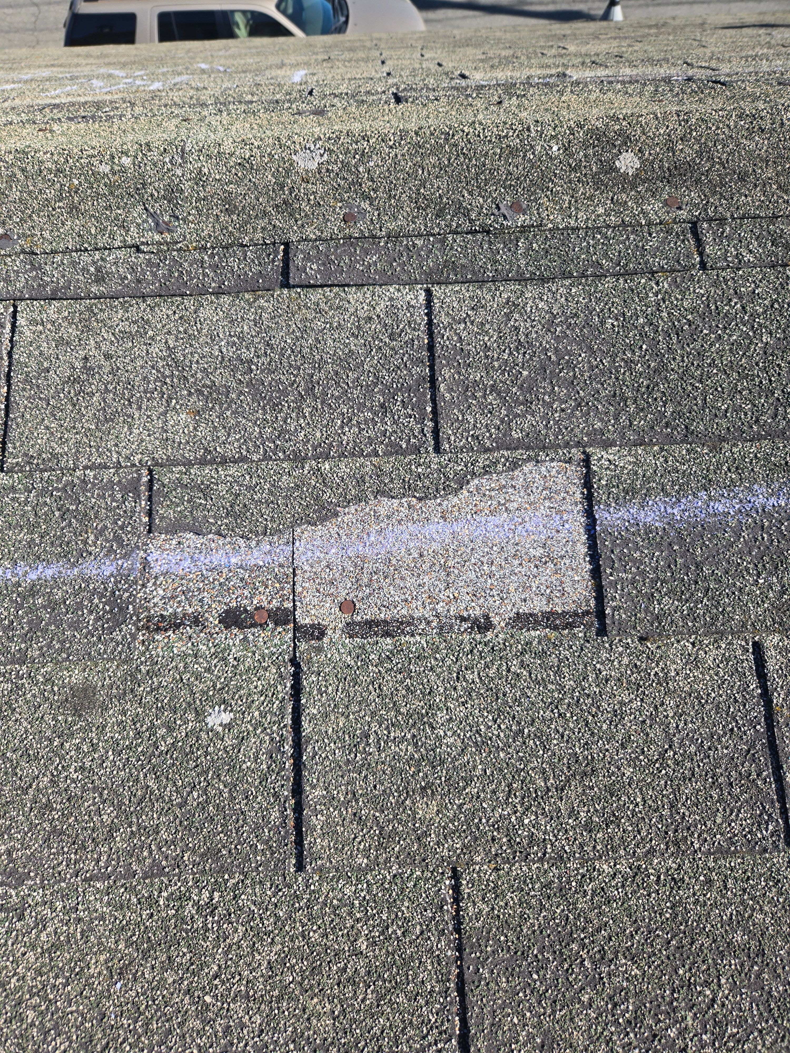Close-up of a wind-damaged shingle marked during the inspection